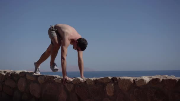 Man praktijk yoga op de rotsachtige strand. — Stockvideo