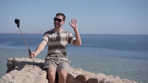 4k - heureux touriste fait selfie avec caméra d'action et selfie bâton sur la plage — Video