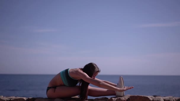 Молодая девушка занимается йогой на пляже . — стоковое видео