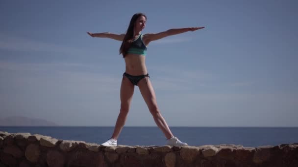 Menina faz pose de tiângulo de ioga na praia . — Vídeo de Stock