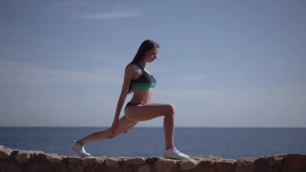 Menina faz prática de ioga na pedra da praia do oceano . — Vídeo de Stock
