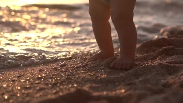 Cute close up shot legs of the baby that makes steps on the sand beach. — Stock Video