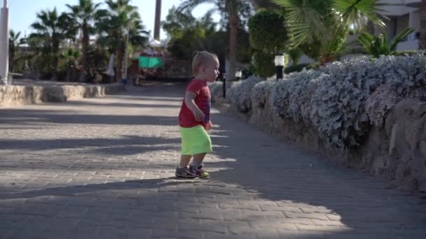 Kleiner Junge in kurzen Hosen läuft in Zeitlupe am Strand entlang. — Stockvideo