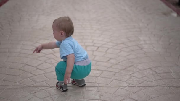 Schattige kleine baby staat op de straat en tonen zijn vinger in slow motion. — Stockvideo
