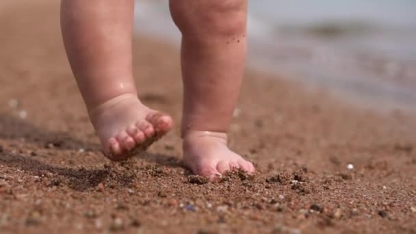 Küçük bebeğin sevimli küçük bacaklar plajda kum duruyor. — Stok video