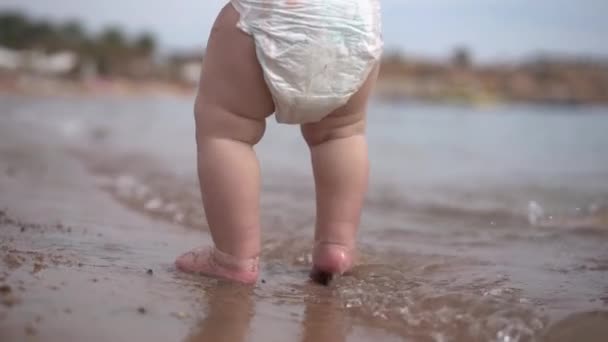 Ноги молодой матери и маленького ребенка в замедленной съемке стоят в море . — стоковое видео
