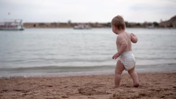 Lindo niño pequeño correr al mar en mimos y se sacude las manos en cámara lenta . — Vídeos de Stock