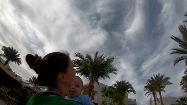 Ragazza getta il bambino nel territorio di un hotel tropicale, girato dal basso — Video Stock