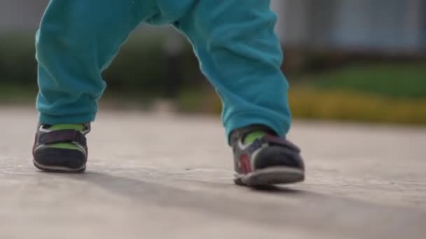 Benen van de kleine jongen in slow motion wandelingen op de straat. — Stockvideo