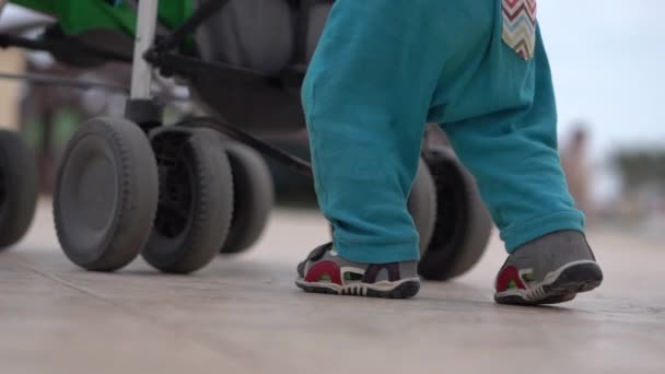 Slow Motion-benen van de kleine jongen en moeder in de buurt van wandelwagen — Stockvideo