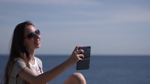 Flicka på stranden gör video samtal och skicka Hello. — Stockvideo