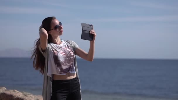 Flickan gör selfie med sin telefon i slow motion på stranden. — Stockvideo