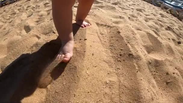 Gambe del bambino piccolo cammina al rallentatore sulla sabbia della spiaggia . — Video Stock