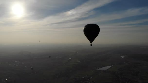 Grande balão de ar quente com uma cesta e pessoas voando sobre um campo ao pôr do sol — Vídeo de Stock
