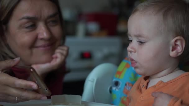 Nonna mostra il nipote che è 1 anno qualcosa su un telefono cellulare — Video Stock