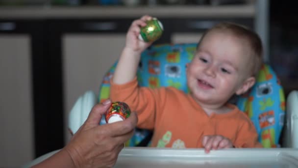 Netter kleiner Junge macht Eierkampf mit der Hand seiner Mutter in Zeitlupe. — Stockvideo