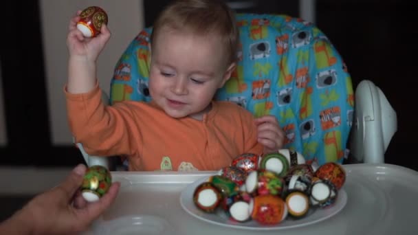 Маленька дитина розважається на кухні він бореться з великодніми яйцями в повільному русі . — стокове відео