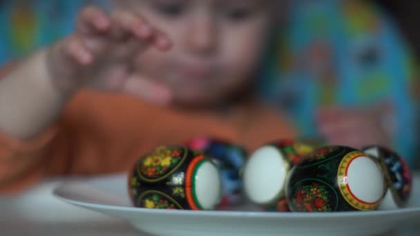 Gros plan des mains bébé qui choisissent des œufs de Pâques sur l'assiette . — Video