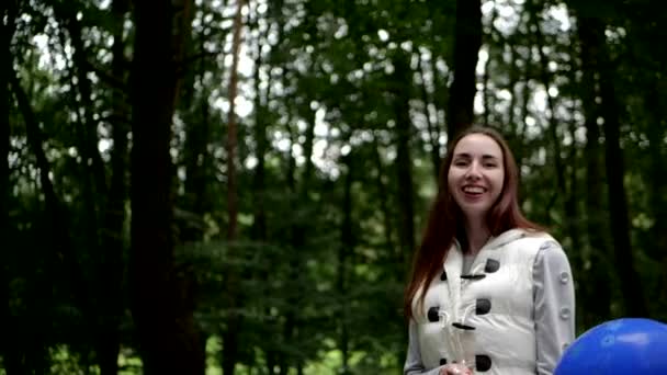 Mujer joven de pie y jugando con un globo en un bosque en primavera — Vídeos de Stock