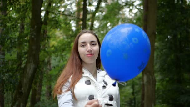Fröhliche Frau steht und schlägt einen blauen Luftballon wie ein Volleyballspieler — Stockvideo