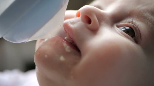 Nice baby drinking water from a bottle with a pipet indoors in slow motion — Stock Video