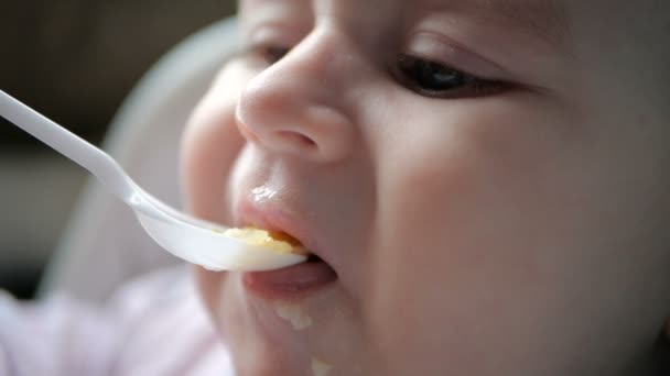 Petit bébé mangeant du porridge d'une cuillère en plastique à l'intérieur au ralenti — Video