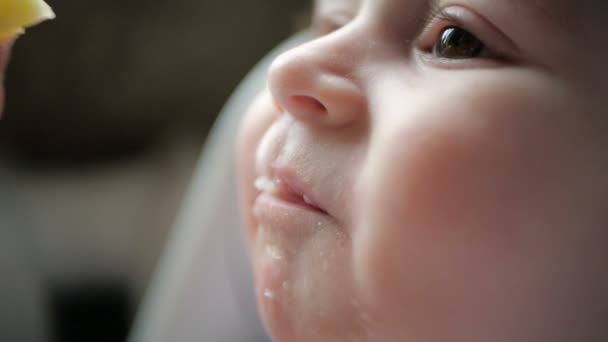 Happy baby zitten en eten pap met een glimlach binnenshuis in slow motion — Stockvideo