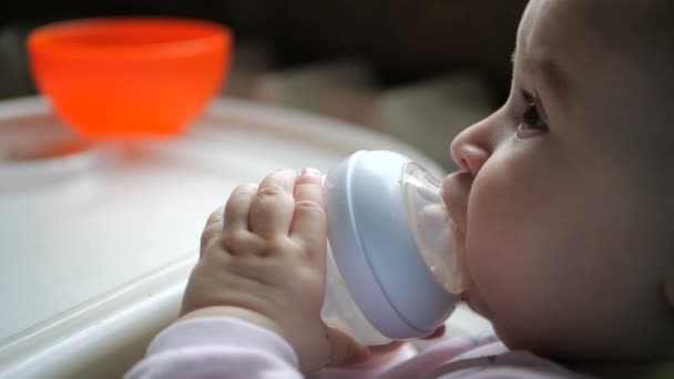 Niedliches Baby sitzt und trinkt Wasser aus einer Flasche mit einer Pipette in Zeitlupe — Stockvideo