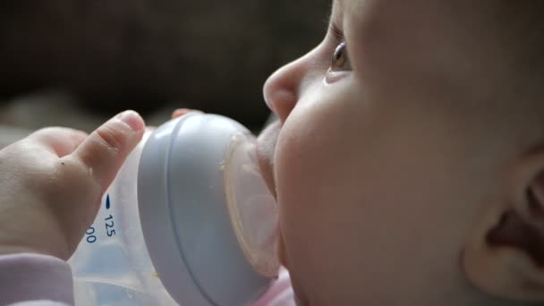 Süßes Baby sitzt und trinkt Wasser aus einer Flasche mit einer Pipette in slo-mo — Stockvideo