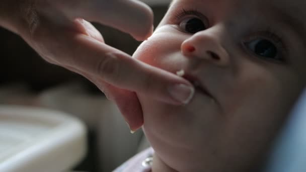 Oprechte baby zitten en eten Kasha van vrouwelijke handen binnenshuis in slow motion — Stockvideo