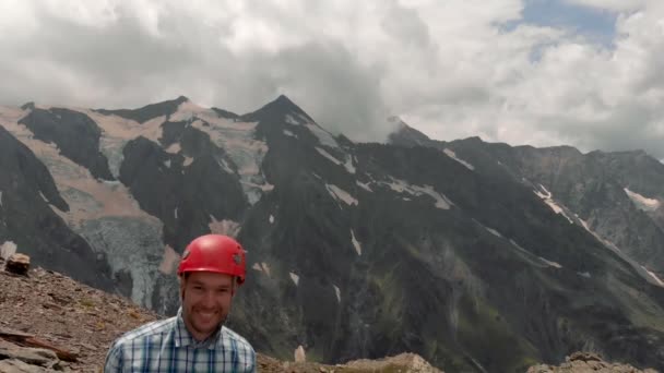 Crazy and funny guy with red helmet show thumb on the cliff mountain. — Stock Video