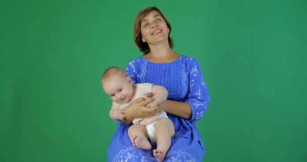 Mãe rola em mãos encantadora criança sorridente em câmera lenta na tela verde — Vídeo de Stock