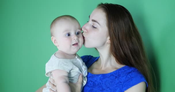 4k - Jovem mãe de vestido azul beija um bebê bonito de 6 meses de idade em câmera lenta — Vídeo de Stock