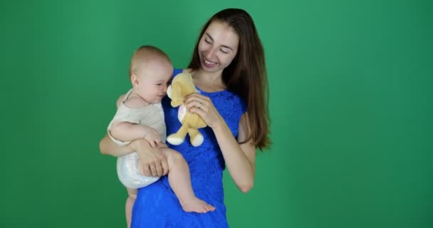 4k - 一个年轻的女孩抱着一个可爱的幼儿在工作室的铬制背景 — 图库视频影像