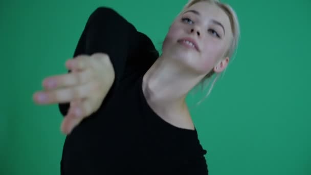 4k - 年轻的金发女孩在工作室在慢动作的绿色背景跳舞 — 图库视频影像