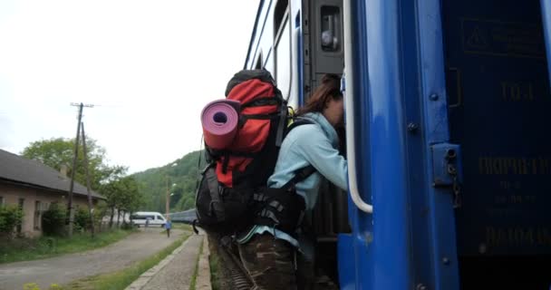 Genç bayan turist ağır çekimde bir trenin merdivenlerinden tırmanıyor. — Stok video