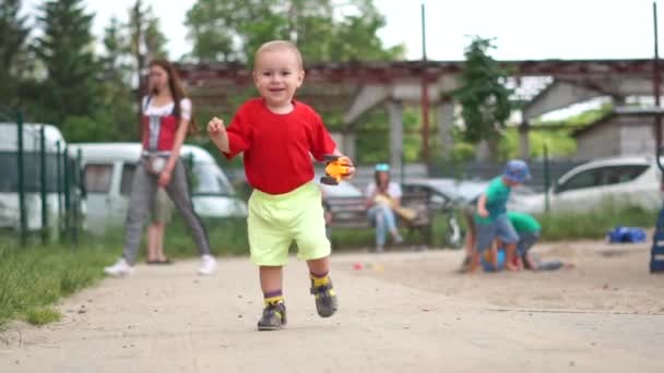 Маленький мальчик со сломанной игрушечной машиной счастливо бежит в замедленной съемке — стоковое видео
