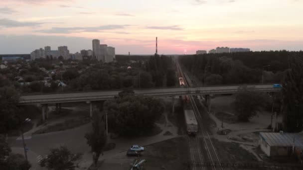 Disparo aéreo de un tren en movimiento, un puente de coche sobre el ferrocarril en Kiev al atardecer — Vídeos de Stock
