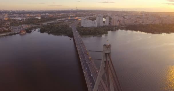Aerial of riding cars on a wide suspension bridge over the Dnipro and the Ukrainian flag — Stock Video