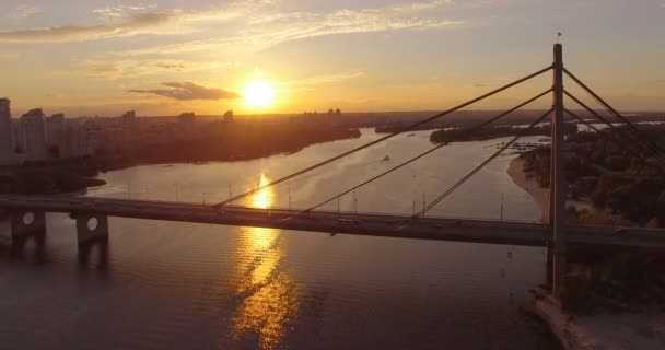 Aerial of a small tug ship and a barge moving at a bridge over the Dnipro at sunset. — Stock Video