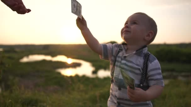 小さな男の子は、スローモーションで自然に数百ドル紙幣を与えられた — ストック動画