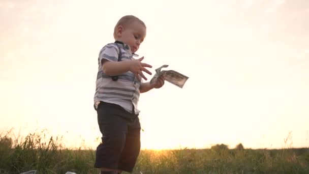 Серьезный маленький мальчик бросает огромную стопку долларовых купюр на землю, замедленная съемка — стоковое видео