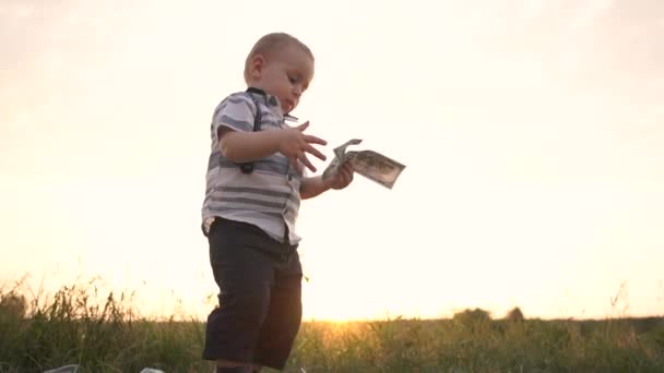 Ernstige kleine jongen gooit een enorme stapel dollarbiljetten op de grond, Slow Motion — Stockvideo