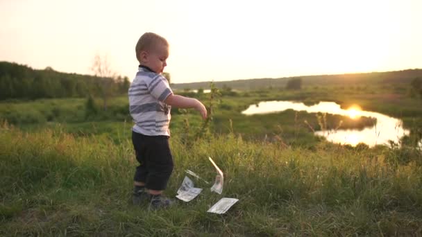 Un petit garçon élégant tient une pile de billets et jette de l'argent au ralenti — Video