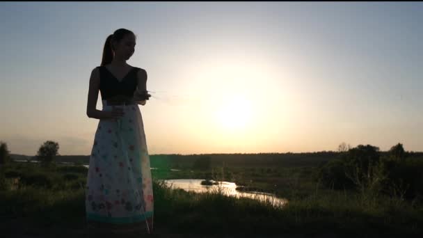 Жінка в сукні робить мильні бульбашки на заході сонця в повільному русі — стокове відео