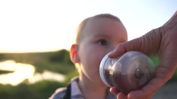 Baby drinkt van een baby fles die moeder houdt bij zonsondergang in slow motion — Stockvideo