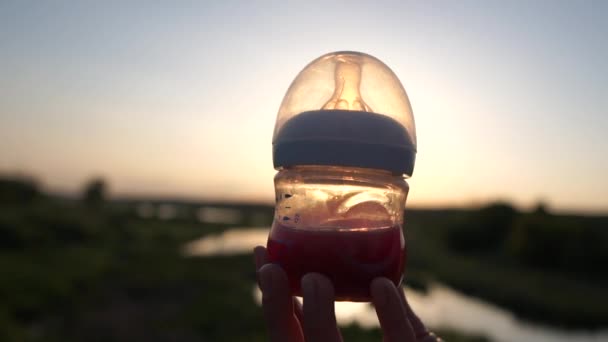 Garrafa de bebê com chupeta contra o sol com líquido em câmera lenta — Vídeo de Stock