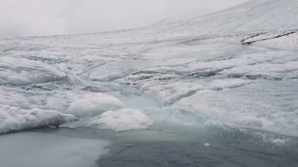 Fluss mit schmelzenden Bächen, die sich in 4k zwischen schneebedeckten Ufern in Bergen bewegen — Stockvideo
