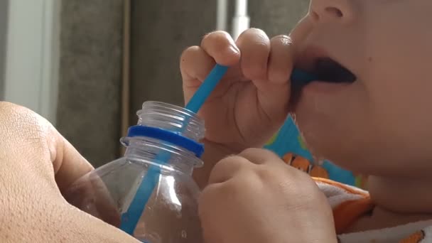 Kleines Kind trinkt Wasser aus Plastikflasche mit Plastikschlauch — Stockvideo