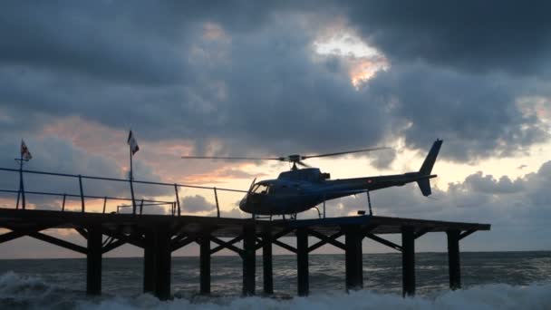 Helicóptero moderno de pie en un muelle de madera en la orilla del Mar Negro en slo-mo — Vídeos de Stock